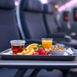 A passenger enjoying a meal on an airplane tray table